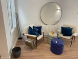 un salon avec un canapé, des fauteuils et un miroir rond