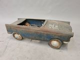 une vieille petite voiture décorée de graffitis, posée sur une surface blanche