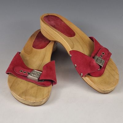 pair of wooden sandals with red straps and buckles on them