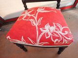 a red chair with white flowers on it in front of a window