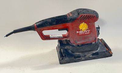 une image représentant une ponceuse électrique rouge et noire posée sur une surface blanche