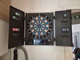un jeu de fléchettes et des fléchettes rangés dans une armoire fixée au mur