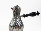an antique silver coffee pot on a stand with a black handle