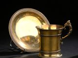 une coupe en or et un plat en argent posés sur une table