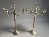 pair of silver plated candelabs with candles on each of them