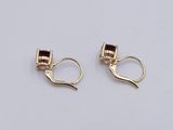 a pair of gold earrings with garnets on them