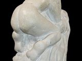 statue of a woman sitting on a rock on a black background