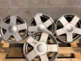 a set of four aluminum wheels on a pallet in a warehouse
