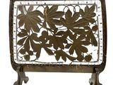 a metal screen with leaves on it on a stand
