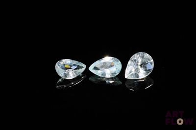 a pair of blue topazte pear shaped diamonds on a black surface