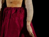 an old fashioned doll with a red dress on a black background