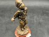 bronze figurine of a boy on a pedestal on a black background