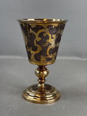 gold and black goblet sitting on top of a white table