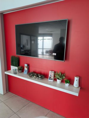 a flat screen tv mounted on a red wall in a living room