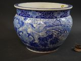 a large blue and white vase with a small coin in front of it