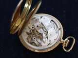 a gold pocket watch on a black surface