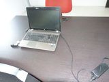 un ordinateur portable posé sur un bureau, avec son chargeur