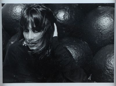 une photo en noir et blanc d'une femme devant un panier d'oranges