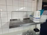 a sink in a kitchen with a metal shelf above it