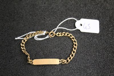 a close up of a gold chain bracelet with a tag on it