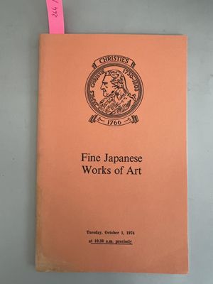 un livre orange posé sur une table, à côté d'un autocollant rose