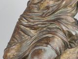 bronze statue of a woman holding a bird on a rock