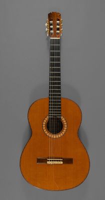 une vieille guitare en bois posée sur une surface grise