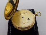 a gold pocket watch sitting on top of a velvet pouch