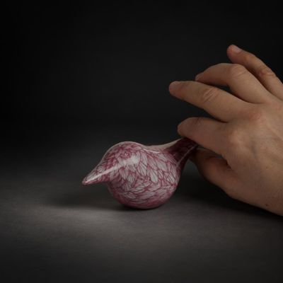 une main tenant un objet rose posé sur une table