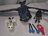 a toothless dragon and other toys sitting on a bed