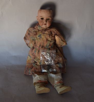 une poupée assise par terre avec un sac