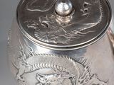 a silver tea pot with a dragon design on it