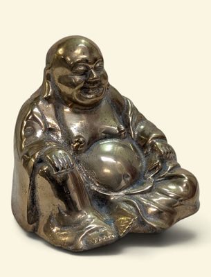a small statue of a smiling buddha sitting on a pillow