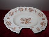 une assiette blanche ornée de fleurs marron, posée sur une table rouge