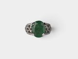 a close up of a ring with a green stone surrounded by white diamonds