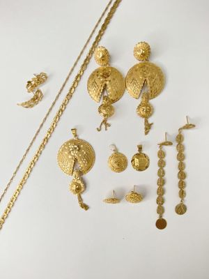 some gold jewelry on a white surface with a white background