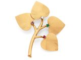 un gros plan d'une broche en or ornée de feuilles et de pierres précieuses