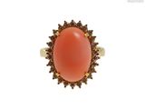 une image représentant une bague ornée d'un corail entouré de diamants bruns