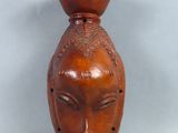 un vase marron orné d'un visage, posé sur une table