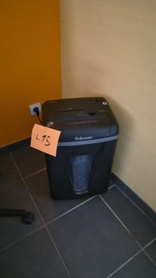 une déchiqueteuse à papier posée par terre près d'un mur