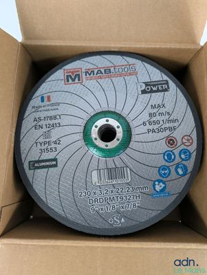 un gros plan d'un disque abrasif métallique dans une boîte en carton
