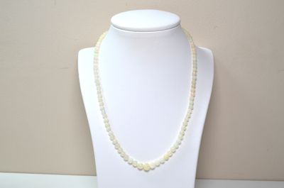 necklace with white beads on a white mannequin with a beige background