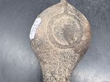 a stone object on a table with a person ' s finger