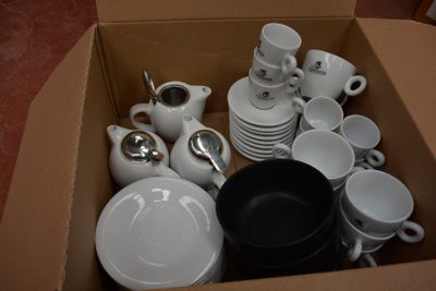 une boîte remplie d'assiettes, de tasses et de cuillères blanches