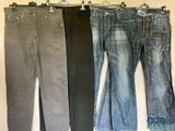 trois paires de jeans suspendues à un portant devant un mur blanc