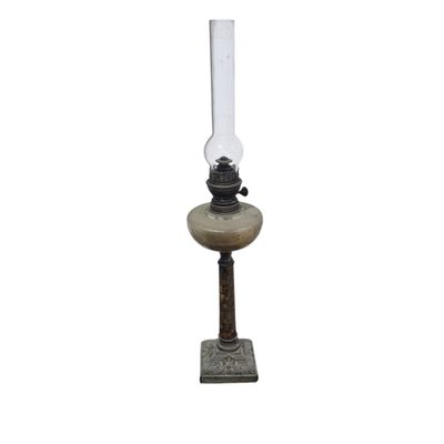une lampe à huile à l'ancienne posée sur un socle, sur fond blanc