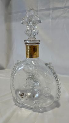 a clear glass bottle with a gold top on a white surface