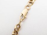 a close up of a gold chain bracelet on a white surface