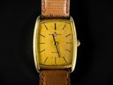 a close up of a yellow watch with a brown strap