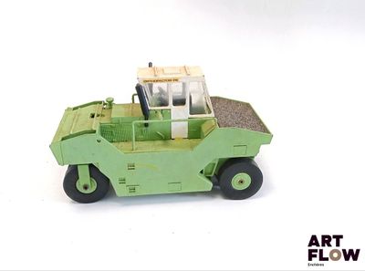 un petit camion jouet vert posé sur une surface blanche